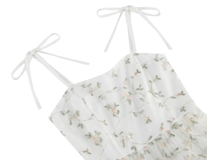 Close-up of pink floral embroidery and adjustable bow straps on white mesh dress