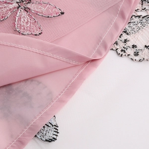 Détail du tissu en maille rose avec broderie papillon élégante et couture précise