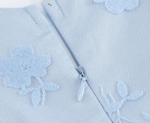 Détail de la fermeture éclair invisible et dentelle florale bleu clair d'une robe sans manches