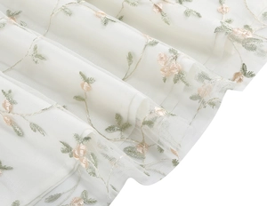 Close-up of pink floral embroidery and leaf patterns on premium white mesh dress fabric
