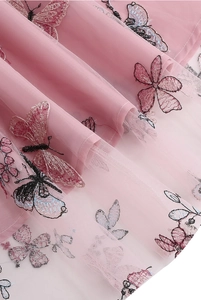 Gros plan sur un tissu en mesh rose avec détails de broderies papillons et fleurs