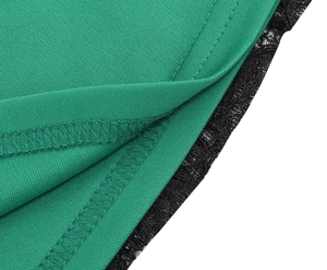 Détail du tissu vert avec bordure en dentelle noire et finitions de couture soignées
