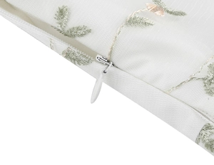 Close-up of the invisible zipper and floral embroidery on white mesh dress fabric