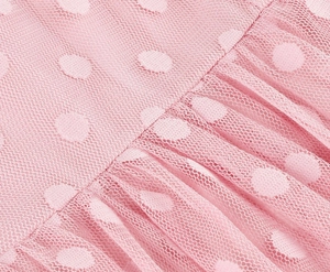 Macro detail of pink Swiss dot mesh fabric with elegant pleated texture on the dress