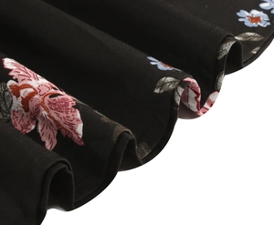Close-up of vintage black floral print fabric with pink and blue blossoms and ruffled texture