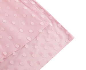 Close-up detail of pink sheer mesh fabric featuring elegant polka dot texture and pattern