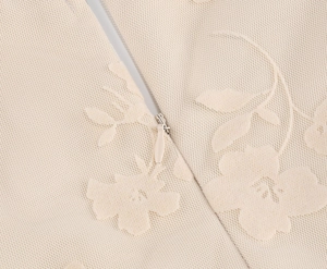 Détail macro du tissu en dentelle beige avec fermeture éclair invisible et texture fine