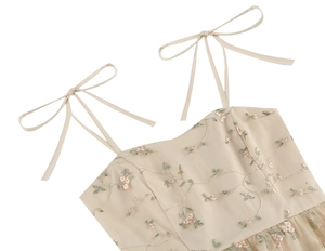 Close-up of floral embroidery details and bow tie straps on a vintage beige mesh dress