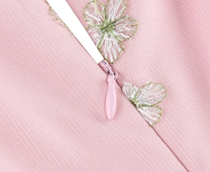 Close-up of invisible zipper detail on pink mesh dress with daisy flower embroidery