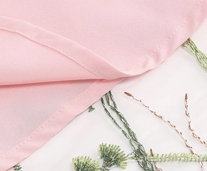 Close-up of pink fabric stitching and floral embroidery on delicate white mesh