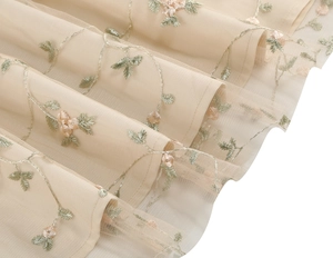 Close-up of delicate floral embroidery on layered champagne mesh evening dress