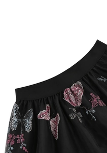 Détail de la broderie de papillons et fleurs sur la jupe en tulle noir transparent