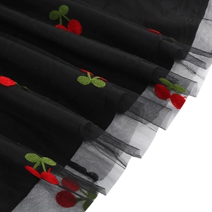 Vue détaillée de la broderie de cerises rouges sur tissu en maille noire pour robe