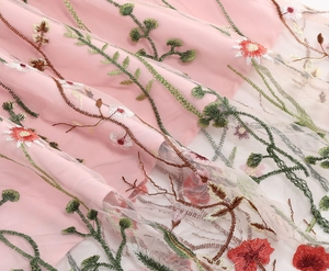 Detailed close-up of colorful floral embroidery on high-quality pink mesh dress fabric