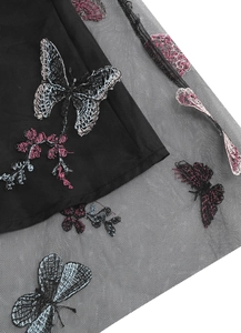 Gros plan sur la broderie de papillons et fleurs sur le tissu en tulle noir de la jupe