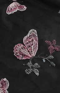 Gros plan de broderie de papillon sur tulle noir avec des fils roses et blancs élégants