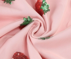 Close-up of pink mesh fabric featuring red strawberry sequin embroidery and petal pleats