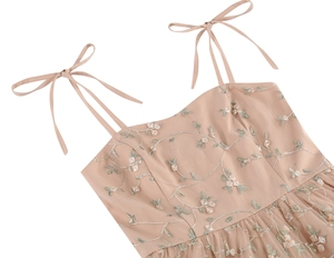 Close-up of floral embroidery on sheer mesh and adjustable ribbon shoulder strap detail