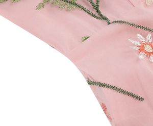 Macro shot of floral daisy embroidery on pink tulle mesh fabric with green vine details