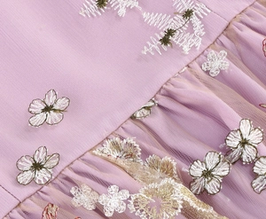 Detailed close-up of light purple mesh fabric with intricate 3D floral embroidery
