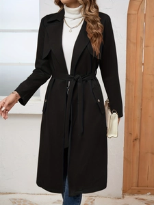 Detail of elegant black faux suede trench coat featuring matching belt and lapel collar