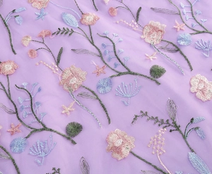 Macro detail of intricate floral embroidery on purple sheer tulle fabric for evening gown