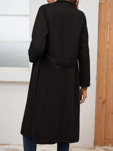 Rear view of a black long trench coat featuring a back waist belt and slim-fit silhouette