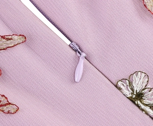 Detailed view of embroidery with butterfly and flower patterns and hidden zipper