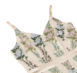 Detail of floral embroidery on a V-neck cream mesh evening dress with thin straps