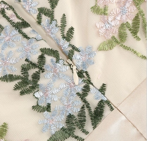 Close-up of floral embroidery and invisible zipper on mesh V-neck evening dress