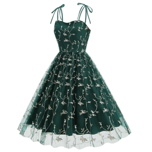 Detail of dark green mesh dress featuring golden floral embroidery and bow shoulder straps