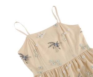 Close-up of champagne mesh dress featuring white floral and blue dragonfly embroidery