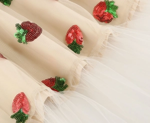 Detail showing red strawberry sequins on multi-layered champagne tulle fabric for kids dress