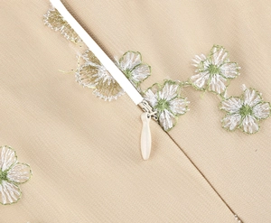 Close-up of invisible zipper and floral embroidery on apricot cocktail dress