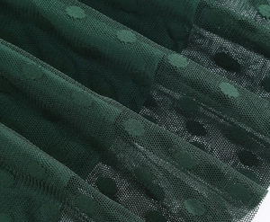 Close-up of dark green polka dot mesh fabric detail with fine texture for vintage cocktail dress