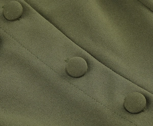 Détail macro du tissu vert olive avec boutons recouverts de tissu et coutures fines