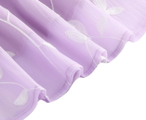 Detail eines lavendelfarbenen Chiffonkleids mit Blattstickerei und sanftem Wellensaum