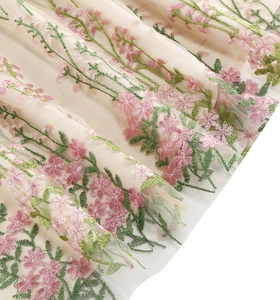 Macro view of floral embroidery on light beige mesh fabric of this elegant V-neck gown