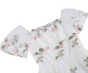 Detail of floral embroidery on white mesh fabric of a vintage off-shoulder cake dress