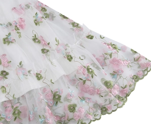 Macro shot of white mesh dress featuring delicate floral embroidery and scalloped hem