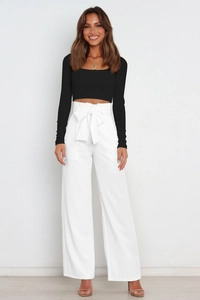 Detail of high-waisted white wide-leg trousers featuring a large elegant matching waist bow