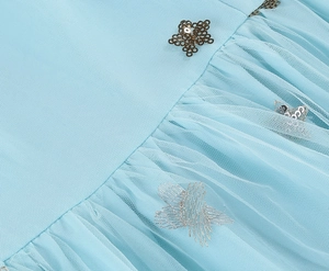 Detail of light blue mesh fabric with golden star sequins and silver embroidery