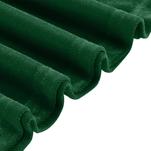 Dettaglio della texture in velluto verde scuro e del drappeggio dell'abito con scollo a V