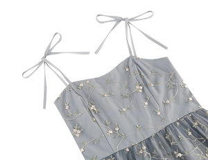 Detail of grey mesh dress featuring pink floral embroidery and bow tie shoulder straps