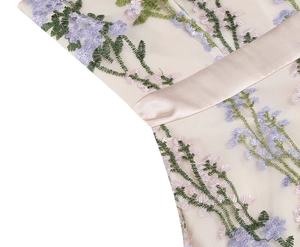 Detailed close-up of floral embroidery on pink mesh and satin waist belt of the dress
