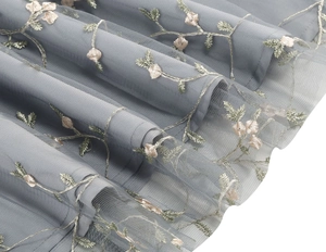 Detail showing delicate floral embroidery on layered grey tulle fabric of a vintage gown