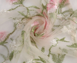 Close-up of floral embroidery on off-white mesh fabric for elegant vintage dress