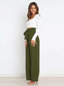 Detail of high-waist paperbag trousers with large olive green bow belt and wide-leg design