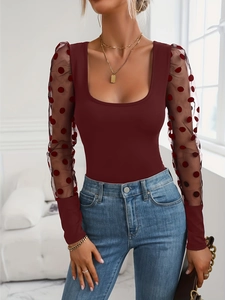 Detail of burgundy fitted top with mesh sleeves featuring red polka dot patterns