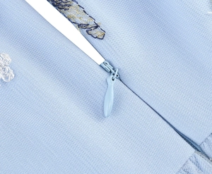 Detail of invisible zipper and intricate embroidery on light blue cocktail dress